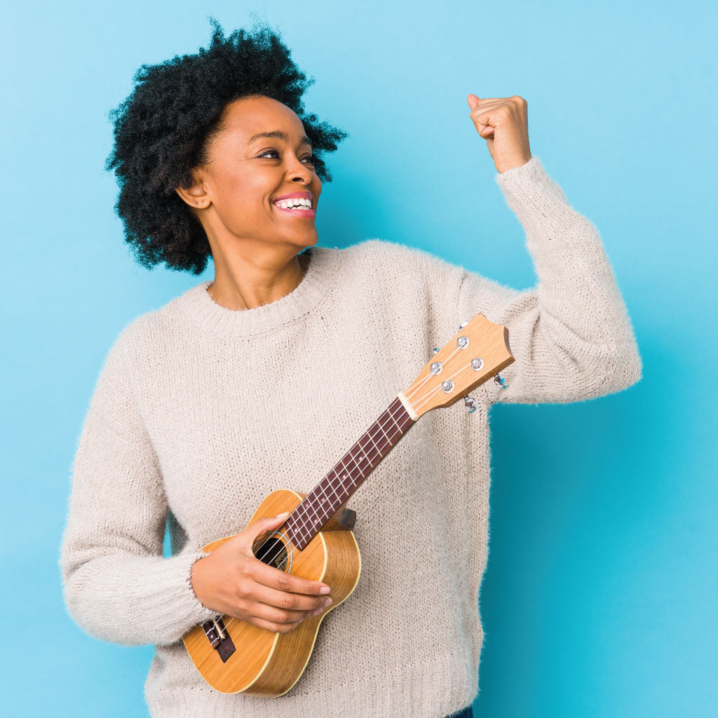 happy woman holding a ukulele on a blue background