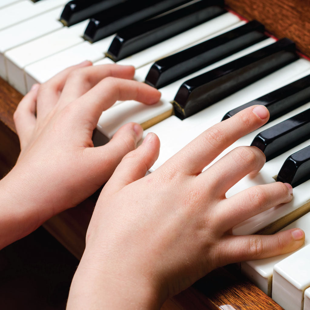 Young hands playing an upright piano